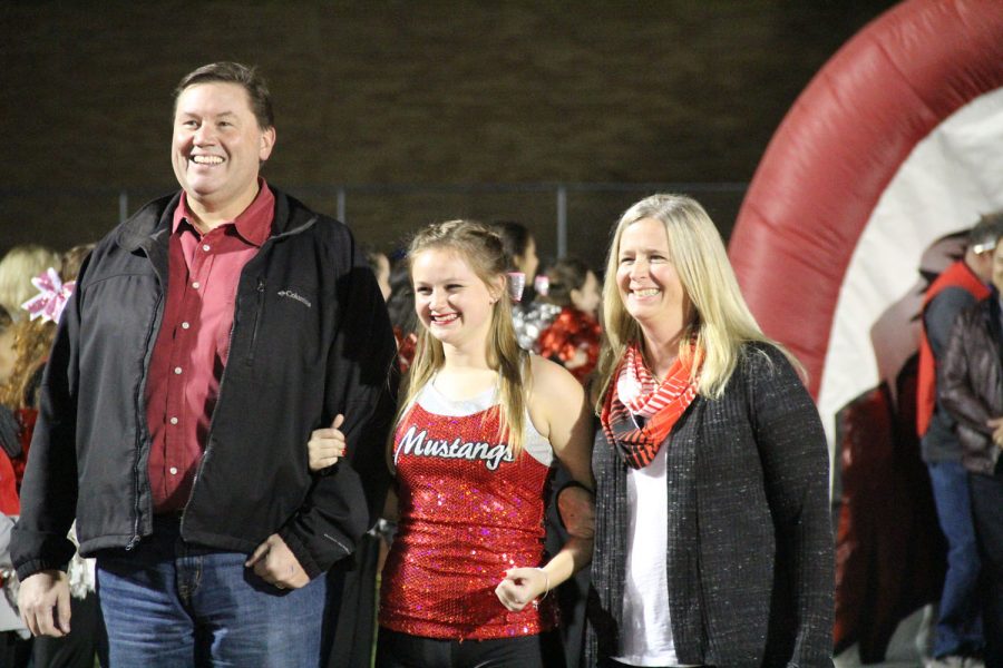 Alexis Brown, senior, walks with her parents onto the football field for senior night.