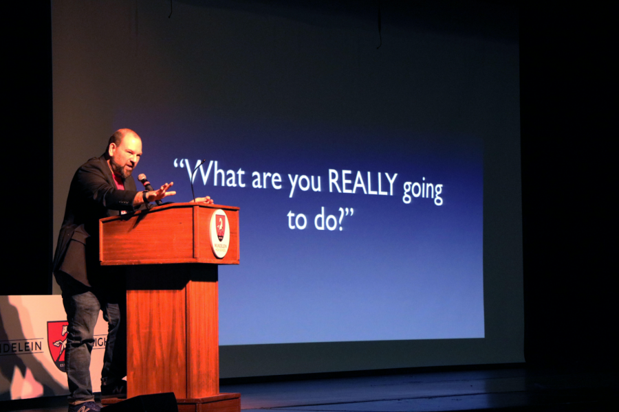 While explaining his background, guest speaker Barry Lyga, promotes his books to his audience on Feb. 25 in the school Auditorium. Lyga engaged his listeners with serial killer fun facts and also explained his methods of writing thriller novels.