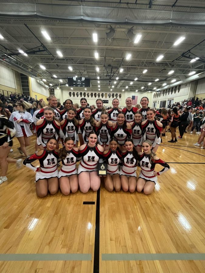 The varsity cheer team sits for a photo at their Invitational on Jan. 14. The smiles of the cheerleaders shine as they bring home their 12th place plaque.
